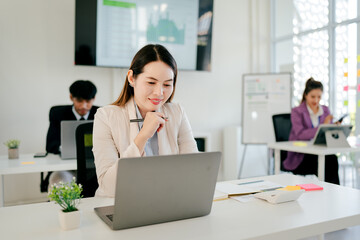 Fototapeta premium Woman is sitting at a desk with a laptop in front of her
