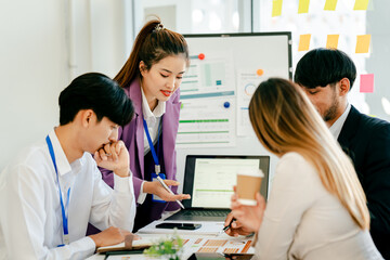 Fototapeta premium Group of people are sitting around a table with a whiteboard and a laptop