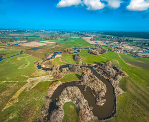 bends of the river on a beautiful sunny spring day over green meadows and fields, forests with blue...