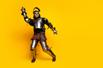 Young man in medieval armor with modern glasses on yellow backdrop displaying contrast of eras and vibrant energy