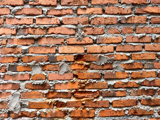 Close up of a red brick wall, showing the rough texture of the red brick and drying cement.