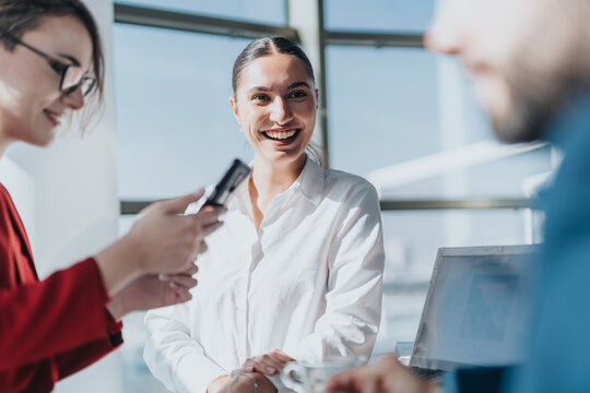 A group of business colleagues engaged in a meeting, showcasing teamwork and positivity in a bright and modern office environment. The focus is on communication and professional interaction.