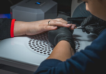view of the work of a beautician in a beauty salon, painting a woman's nails, hands and salon equipment in the form of nail polish testers, painting nails