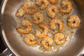 Close-up of delicious seasoned shrimp saut√©ing in a pan. Perfect for food blogs and culinary websites.