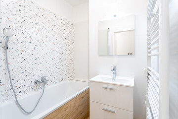 Modern bathroom interior showing bathtub, sink, and heated towel rail