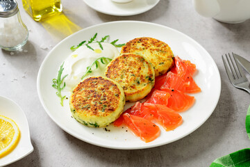 Salted cottage cheese pancake with greens, served with smoked salmon slices and sour cream. Healthy breakfast. Light gray background. 