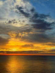 Sunset sky clouds and dark shiny ocean