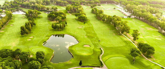 A panoramic aerial view of a golf course with a scenic pond and lush greenery.