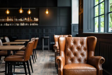 Fototapeta premium A cozy cafe interior featuring stylish brown leather chairs, wooden tables, and elegant lighting, creating a warm and inviting atmosphere.
