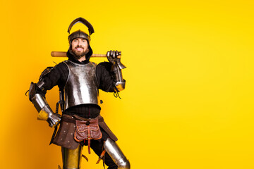 Fototapeta premium Young man in knight armor on vibrant yellow background evokes medieval themes with a modern twist