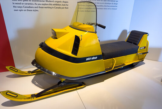 Victoria, British Columbia, Canada. Feb 24, 2025. A vintage yellow Ski-Doo snowmobile displayed indoors, angled, with text panels visible in the background, showcasing its classic design.