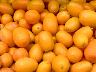 Fresh kumquats displayed at a vibrant market during sunny harvest season