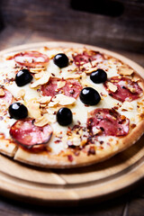 Pizza with salami and mozzarella cheese. Wooden background. Soft focus. Close up.
