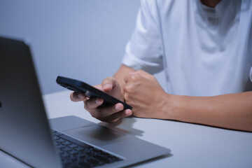 Fototapeta premium Cropped shot of young businessman hand typing on smartphone or laptop computer while working in office room.