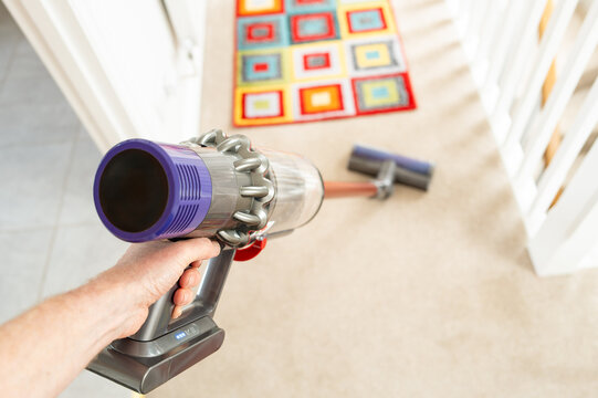 Shallow focus of the filter section of a well-known cordless carpet and multi tool cleaner. The home owner is using it to clean a bedroom carpet in a typical household environment.