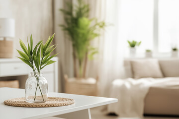 A minimalist study with a small bamboo plant in a clear glass vase on a white desk, accented by neutral decor and soft natural light