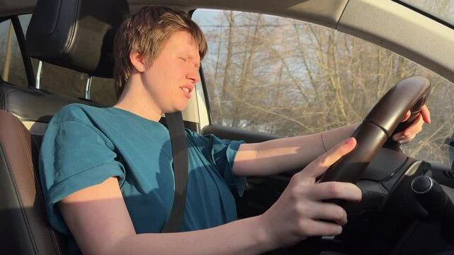 young woman with short haircut behind the wheel has problems with driving because of sun in eyes in cold season