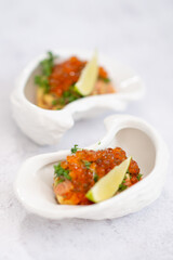 Salmon tartare appetizer with caviar. Mini tartlets with red salmon caviar and smoked salmon, an appetizer idea for a festive table