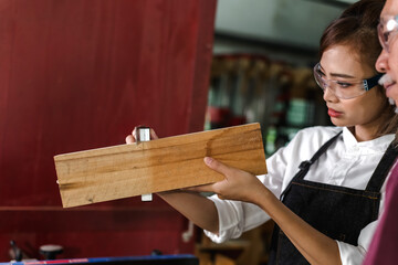 Asian female carpenter checking wood working with diy work in carpentry 