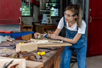 Young Asian female carpenter working with diy wood work in carpentry work place