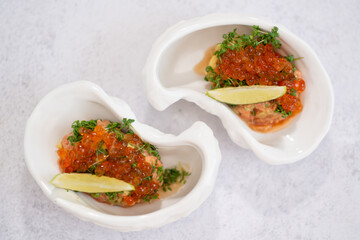 Salmon tartare appetizer with caviar. Mini tartlets with red salmon caviar and smoked salmon, an appetizer idea for a festive table