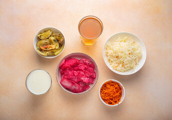 Sauerkraut, pickled cabbage, pickled cucumbers and tomatoes, fermented carrots, kefir and kombucha are arranged on a table, offering a variety of probiotic rich foods beneficial for gut health