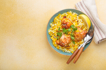 Delicious indian chicken biryani with chicken, garnished with fresh cilantro and lemon, in a bowl...