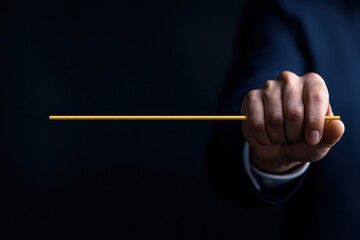 A businessman confidently holds a thin stick against a dark background.
