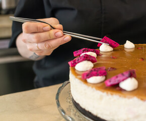 Woman pastry chef decorating a caramel cheesecake with dragon fruit