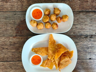 Pile of baked shrimp ball and pork fried Wontons served on a white plate with sweet and spicy...