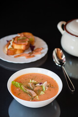 Thick and creamy cream soup of trout in a plate, isolated on black background
