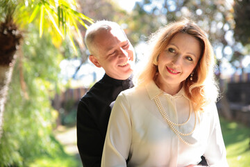 Fototapeta premium Priest smiling and embracing elegant woman in garden setting