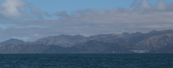 Delightful sea landscape with blue surface of the water, magic feather clouds on the sky over mountain in Kaikoura,New Zealand