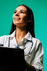 Healthcare professional smiling while looking up in a studio with a green backdrop, conveying...