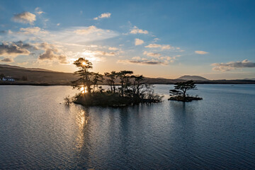Lough Bofin’s islands glow at dusk, golden light on calm waters, Connemara’s serene beauty, Ireland