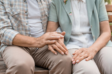 Senior couple, park and holding hands for bonding, support and marriage together outdoors. Retirement, empathy and elderly man with women in nature on bench for love, compassion and connection