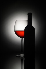 Elegant red wine glass and bottle silhouette against a soft light backdrop at an intimate setting
