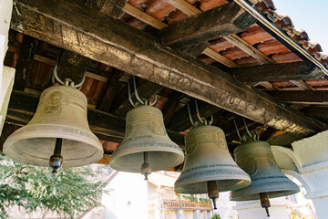 Row of bells under the roof of the bell tower of an ancient church