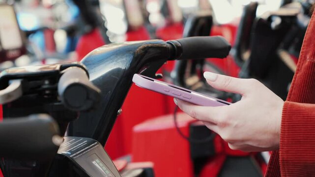 Person takes a electric bicycle sharing parking lot. Woman rental bicycle using cell phone app. High quality 4k footage