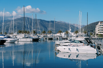 Obraz premium Yachts moored along the piers are reflected in the sea against the background of mountains