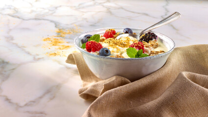 Muesli mit Obst und beigem Tuch auf Marmorplatte in weisser Schale, Muesli, Körner, Obst, Himbeeren, 