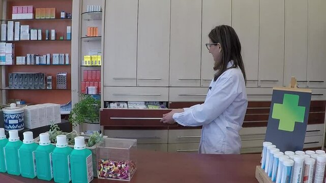 smiling female pharmacist working behind a pharmacy counter