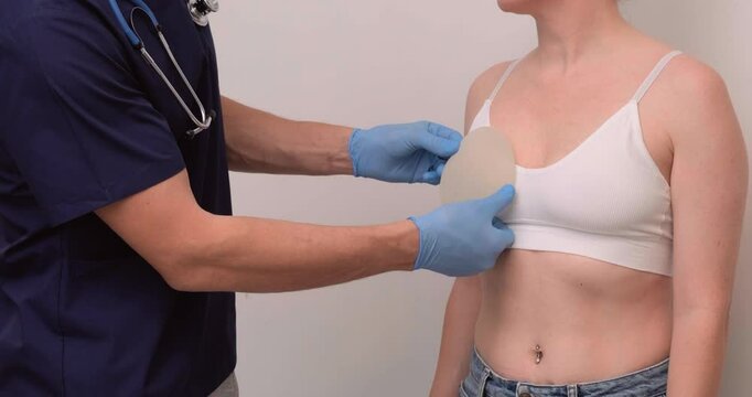 doctor and patient, exam, consultation in clinic office, holding breast enlargement implant in hands, plastic surgery, beauty enhancement, medical Mammoplasty and plastic surgery, mastopexy