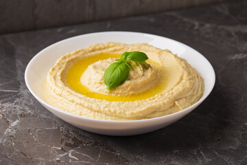 A view of a plate of homemade hummus with olive oil on dark stone table. Arabic cuisine. Isometric style.