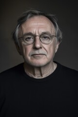 Obraz premium Thoughtful senior man with a gentle expression and distinguished features in moody lighting.