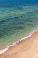 Waves gently lap at the golden shoreline, where the turquoise sea meets soft sand. This tranquil scene invites relaxation, a perfect escape into nature’s soothing embrace.
