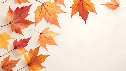 Fototapeta premium Beautiful Autumn Leaves Scattered on a Light-Colored Background: Displaying a Variety of Vibrant Fall Colors Including Orange, Red, and Yellow, Highlighting the Beauty of the Autumn Season and the Div