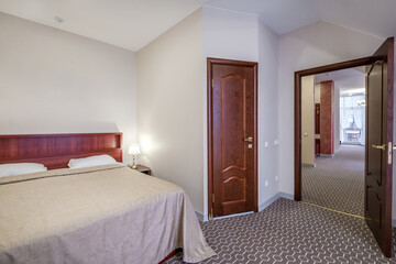 double bed with pillows in interior with night lamp in hotel room