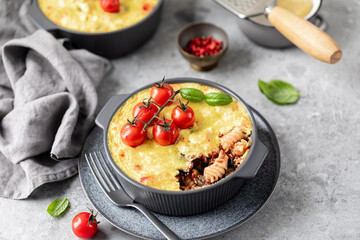 classic Greek pasta dish with a vegetable filling under a cheese crust on a gray background.