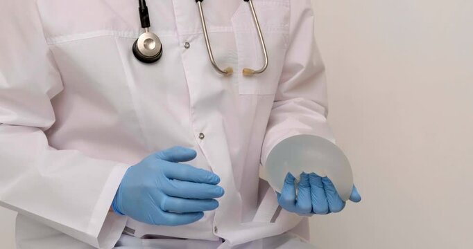 doctor squeezes in his hand breast enlargement implant, plastic surgery, beauty enhancement, medical Mammoplasty and plastic surgery, mastopexy